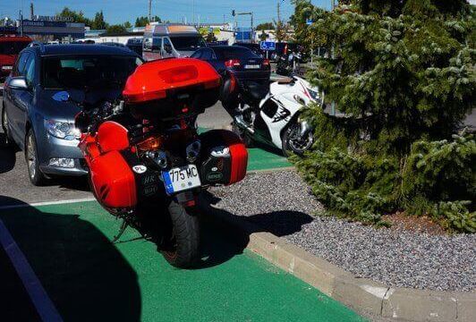 Raudonas motociklas pastatytas motociklui skirtoje parkingo vietoje